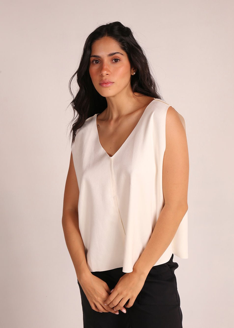 Top sin mangas elaborado en tela de gamuza sintética, con un elegante cuello en V. La prenda es liviana y presenta una silueta recta, ofreciendo comodidad y estilo. Ideal para combinar con pantalones altos, este top es perfecto para ocasiones casuales o salidas elegantes.