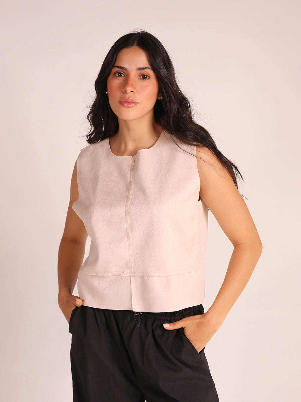 Top sin mangas elaborado en tela de gamuza sintética, con un elegante cuello en V. La prenda es liviana y presenta una silueta recta, ofreciendo comodidad y estilo. Ideal para combinar con pantalones altos, este top es perfecto para ocasiones casuales o salidas elegantes.