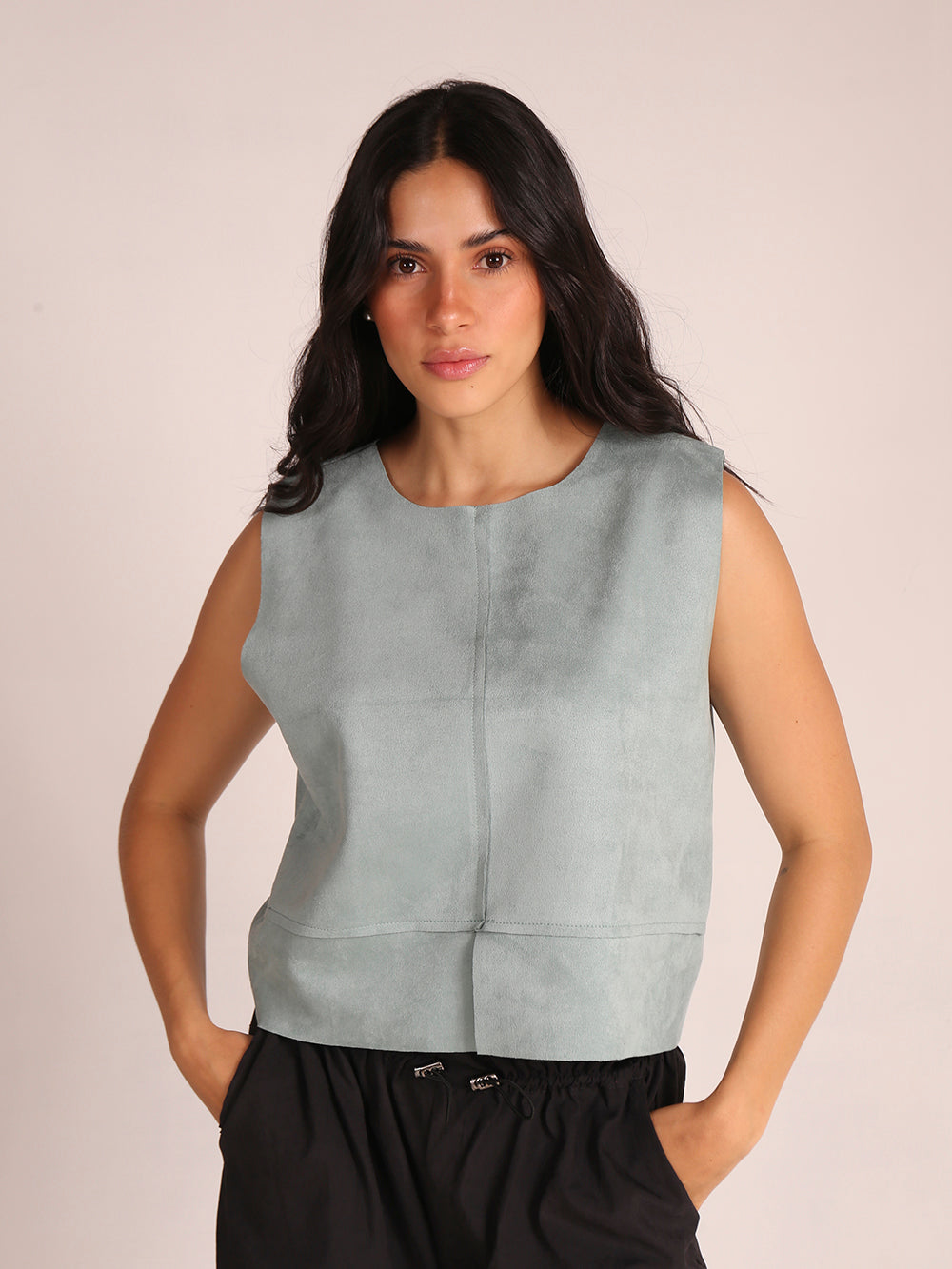 Top sin mangas elaborado en tela de gamuza sintética, con un elegante cuello en V. La prenda es liviana y presenta una silueta recta, ofreciendo comodidad y estilo. Ideal para combinar con pantalones altos, este top es perfecto para ocasiones casuales o salidas elegantes.